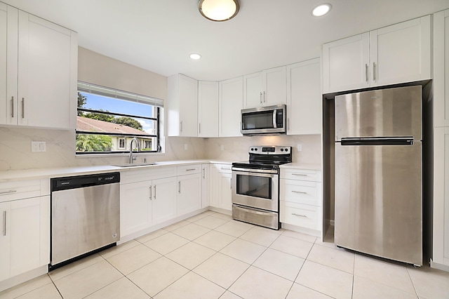 kitchen with sink, white cabinets, decorative backsplash, light tile patterned floors, and stainless steel appliances