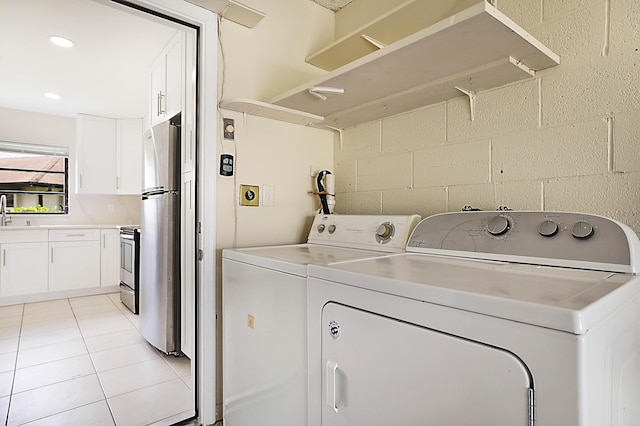 clothes washing area with light tile patterned flooring, sink, and washing machine and dryer