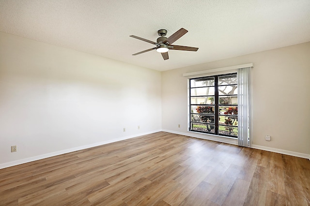 empty room with ceiling fan, a textured ceiling, and light wood-type flooring