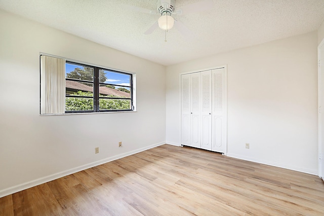 unfurnished bedroom with a textured ceiling, a closet, ceiling fan, and light wood-type flooring