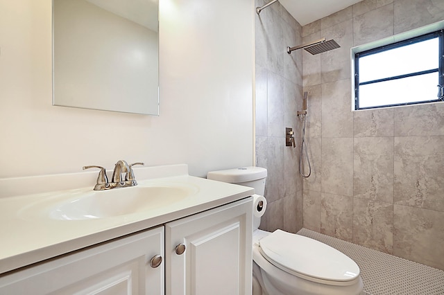 bathroom featuring vanity, a tile shower, and toilet