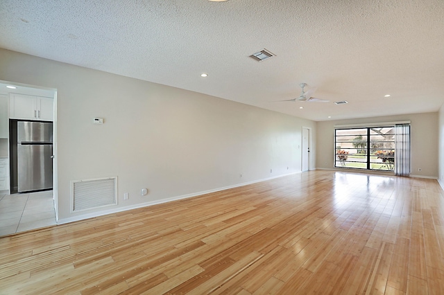 unfurnished room featuring ceiling fan, light hardwood / wood-style flooring, and a textured ceiling