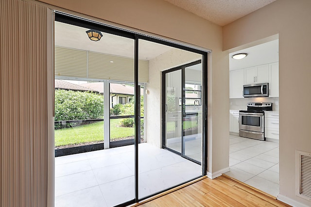 doorway with light hardwood / wood-style flooring and a textured ceiling