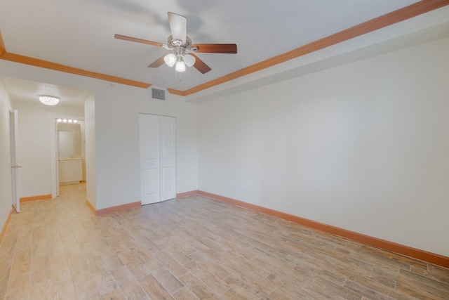 unfurnished bedroom featuring ceiling fan, ornamental molding, a closet, and light wood-type flooring