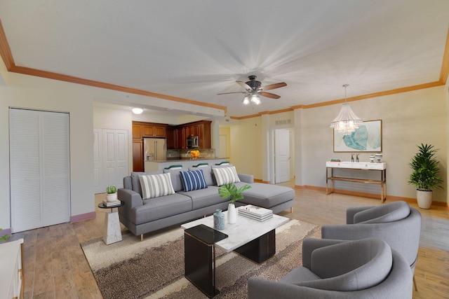 living room featuring crown molding, ceiling fan with notable chandelier, and light hardwood / wood-style floors