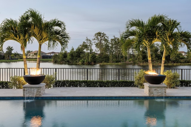 view of swimming pool featuring pool water feature, a water view, and an outdoor fire pit