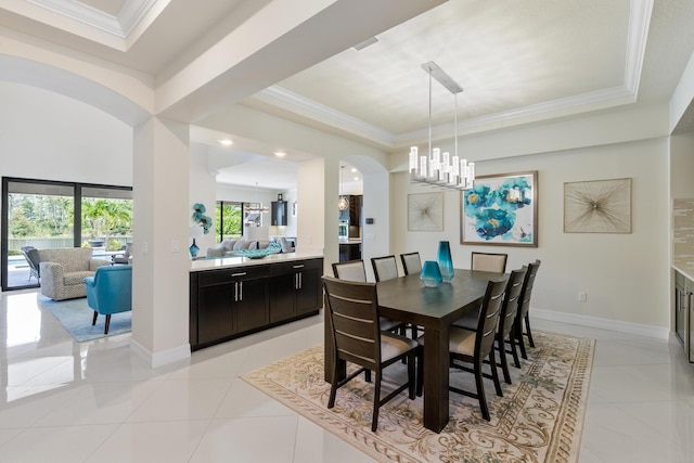 tiled dining room featuring a tray ceiling, crown molding, and an inviting chandelier