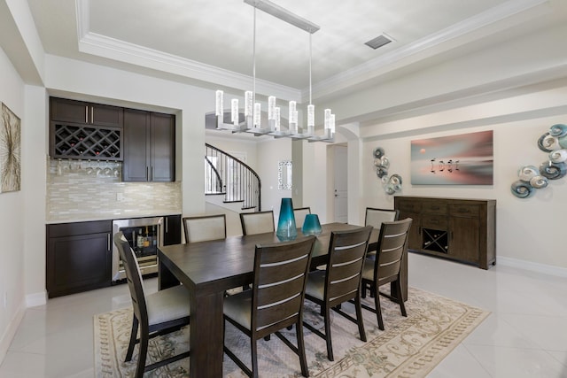 dining room featuring a raised ceiling, wine cooler, crown molding, bar, and light tile patterned floors