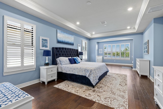 bedroom with dark hardwood / wood-style flooring, a raised ceiling, and ornamental molding