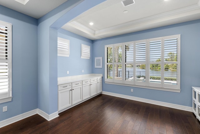 unfurnished room featuring crown molding, a raised ceiling, and dark wood-type flooring