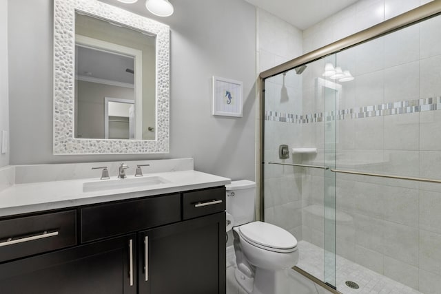 bathroom featuring vanity, toilet, a shower with shower door, and crown molding