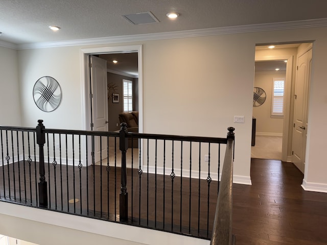 corridor with dark hardwood / wood-style floors, a textured ceiling, and ornamental molding