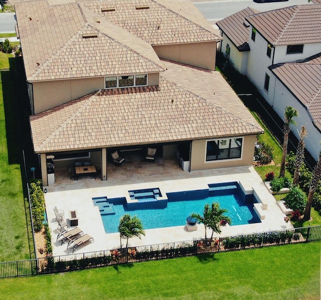 rear view of house featuring a pool with hot tub, a yard, and a patio