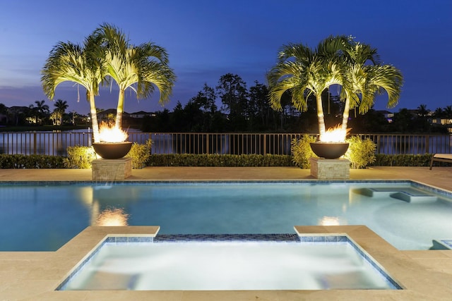 pool at dusk with an in ground hot tub