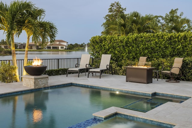 view of pool with an in ground hot tub, a water view, and a fire pit