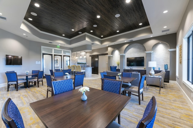 dining space featuring a tray ceiling, wood ceiling, light colored carpet, and ornamental molding