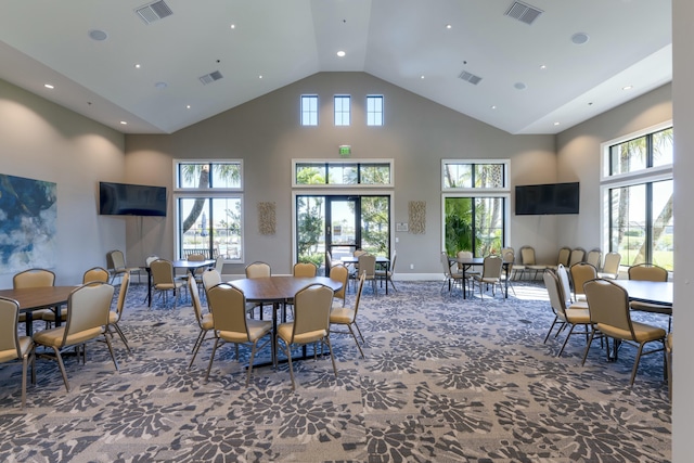 dining area with plenty of natural light, a towering ceiling, and carpet floors