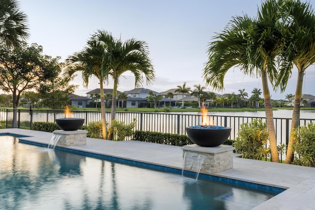 view of pool with pool water feature, a water view, and a patio area