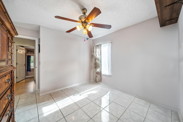 interior space with ceiling fan, a textured ceiling, and light tile patterned flooring