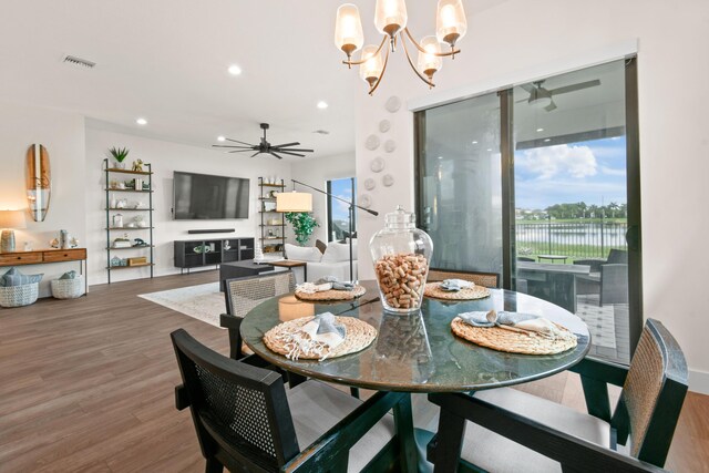 dining area with ceiling fan with notable chandelier and wood-type flooring