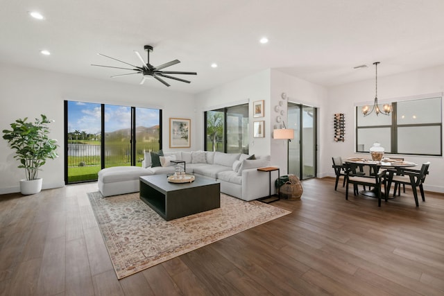 living room featuring ceiling fan with notable chandelier and hardwood / wood-style flooring