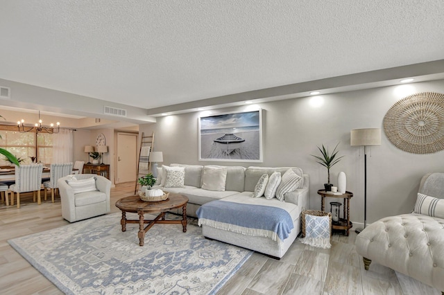 living room featuring a textured ceiling, hardwood / wood-style floors, and a notable chandelier