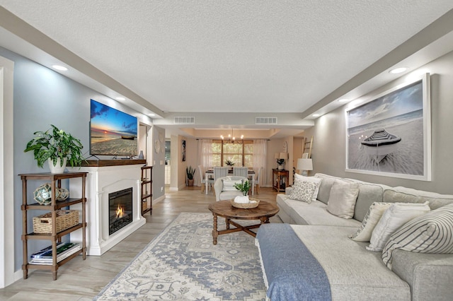 living room featuring an inviting chandelier, wood-type flooring, and a textured ceiling