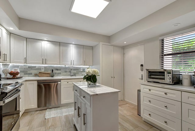 kitchen featuring decorative backsplash, white cabinets, stainless steel appliances, a center island, and light hardwood / wood-style flooring