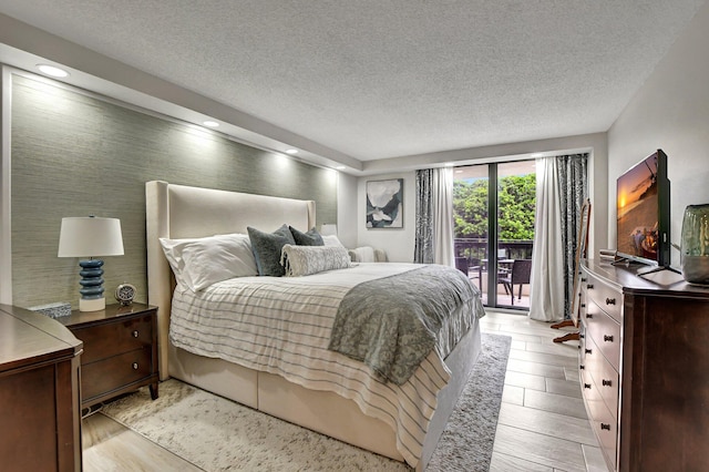 bedroom featuring light wood-type flooring, a textured ceiling, and access to outside