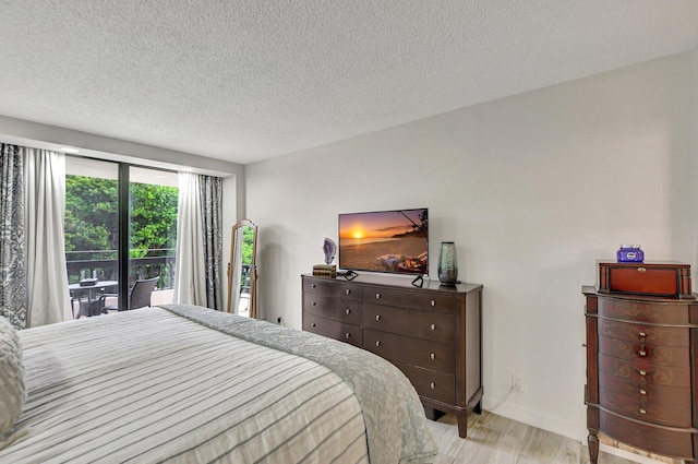 bedroom with a textured ceiling, light wood-type flooring, and access to exterior