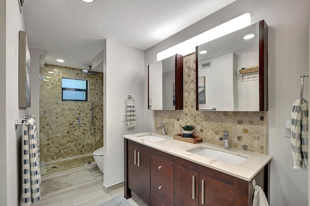 bathroom with vanity, backsplash, an enclosed shower, and toilet