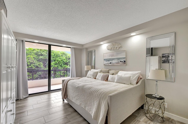 bedroom featuring a textured ceiling, access to outside, and wood-type flooring