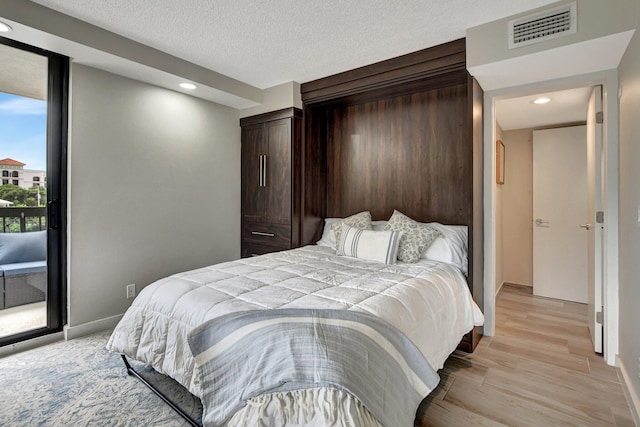 bedroom with light wood-type flooring and a textured ceiling