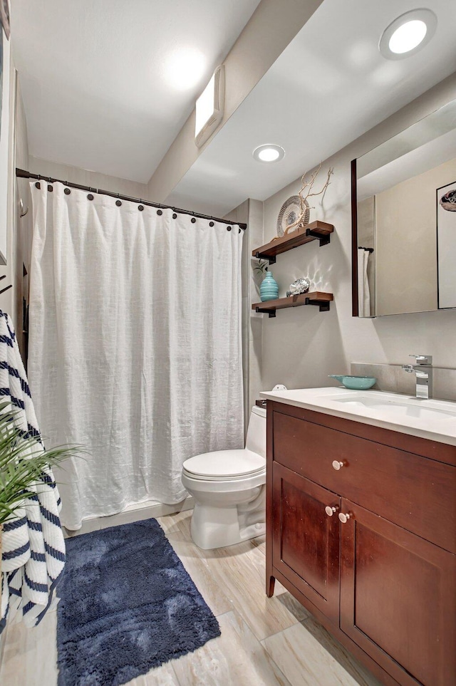 bathroom with walk in shower, vanity, and toilet