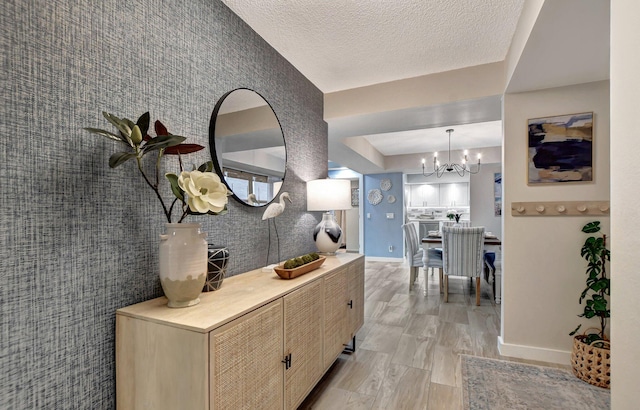 hallway with an inviting chandelier and a textured ceiling