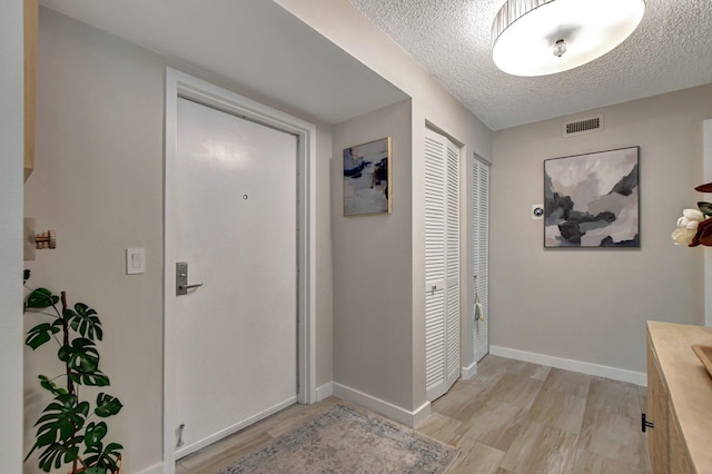 doorway to outside featuring light wood-type flooring and a textured ceiling