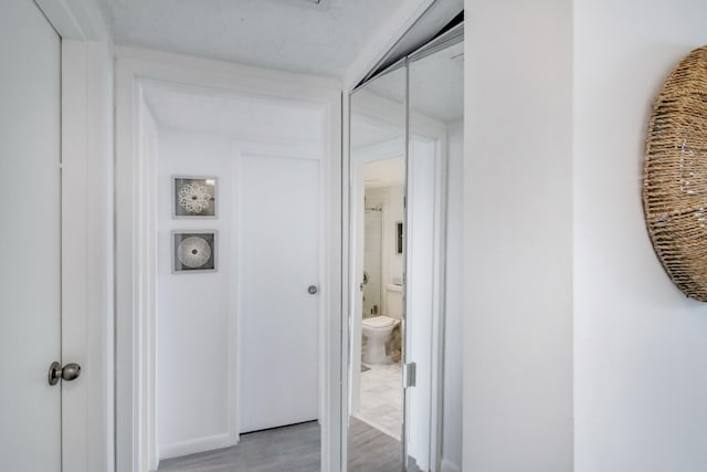 hall with a textured ceiling and light wood-type flooring