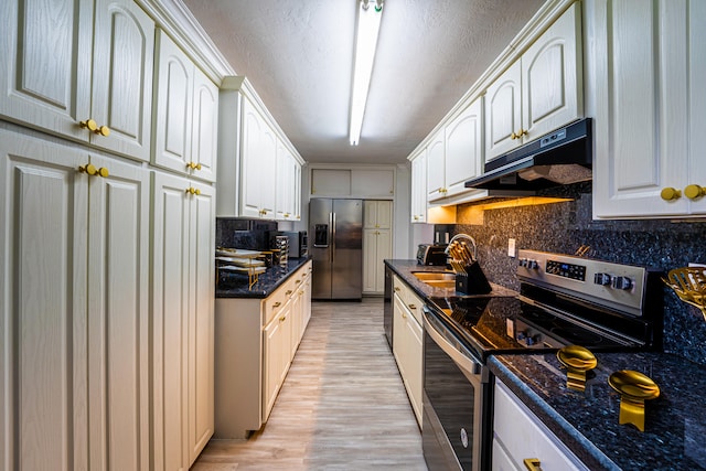 kitchen with white cabinets, backsplash, light hardwood / wood-style flooring, and appliances with stainless steel finishes