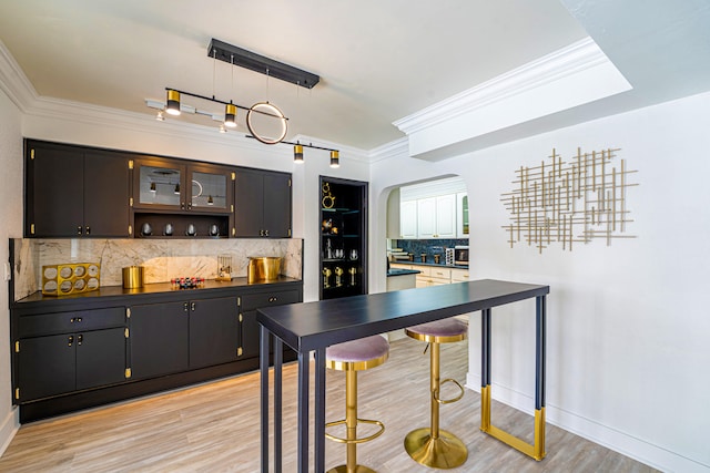 kitchen with light wood-type flooring, backsplash, hanging light fixtures, ornamental molding, and a notable chandelier