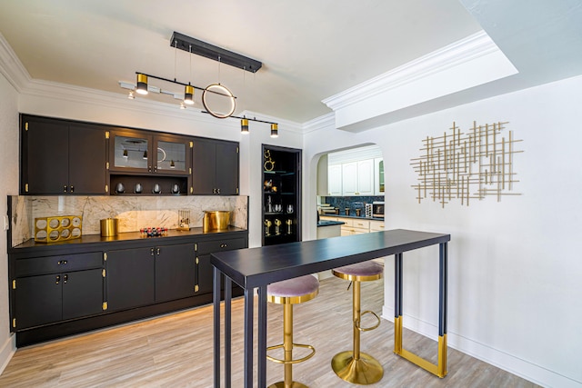 bar with pendant lighting, crown molding, light hardwood / wood-style flooring, and decorative backsplash