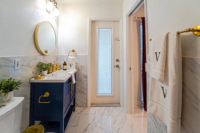 bathroom with vanity, toilet, and tile walls