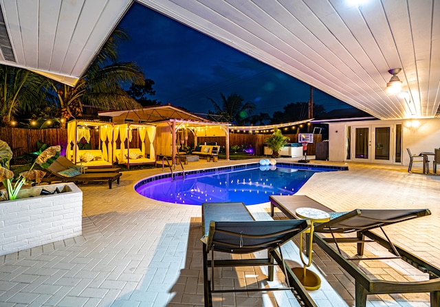 pool at night featuring a patio area and french doors