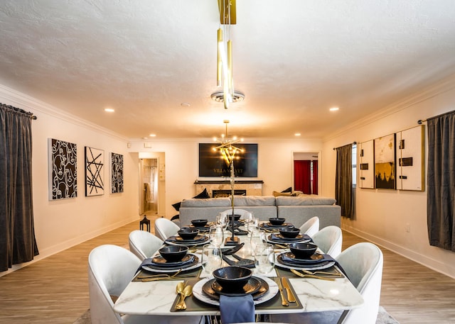 dining room with ornamental molding, a textured ceiling, a notable chandelier, and light wood-type flooring