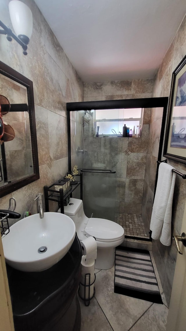 bathroom with toilet, tile walls, sink, tile patterned floors, and a shower with door