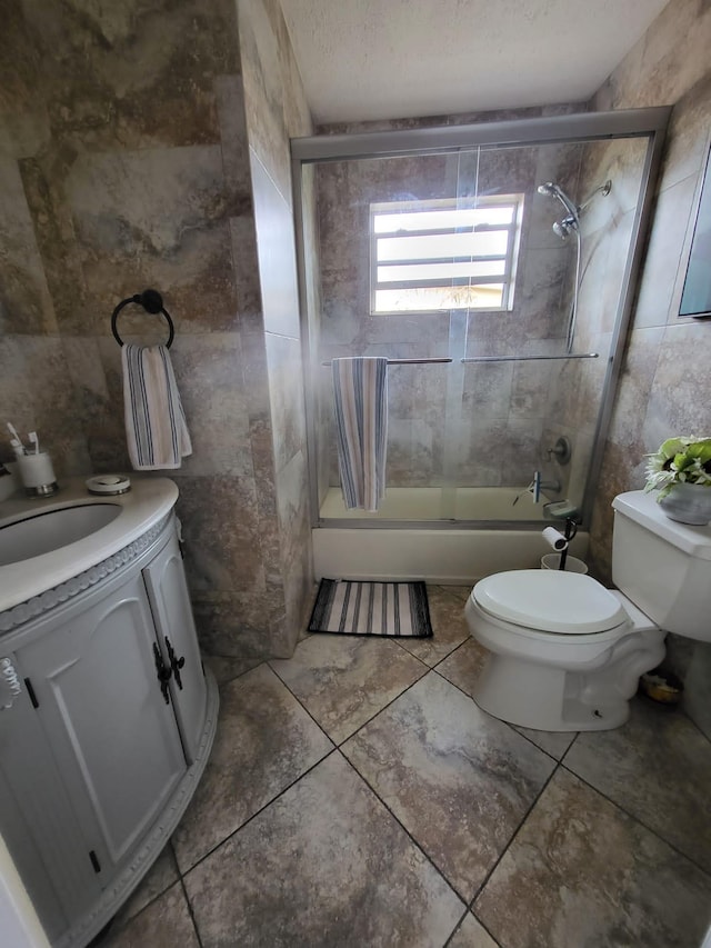 full bathroom with toilet, bath / shower combo with glass door, vanity, and tile patterned flooring