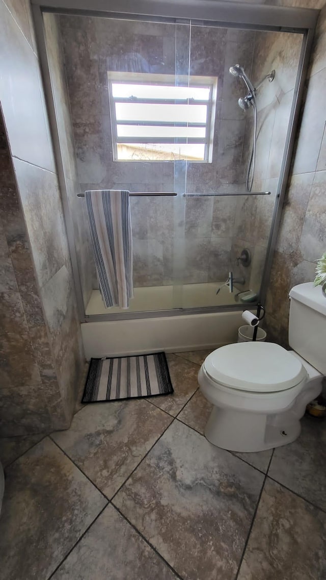 bathroom featuring enclosed tub / shower combo, toilet, and tile patterned flooring