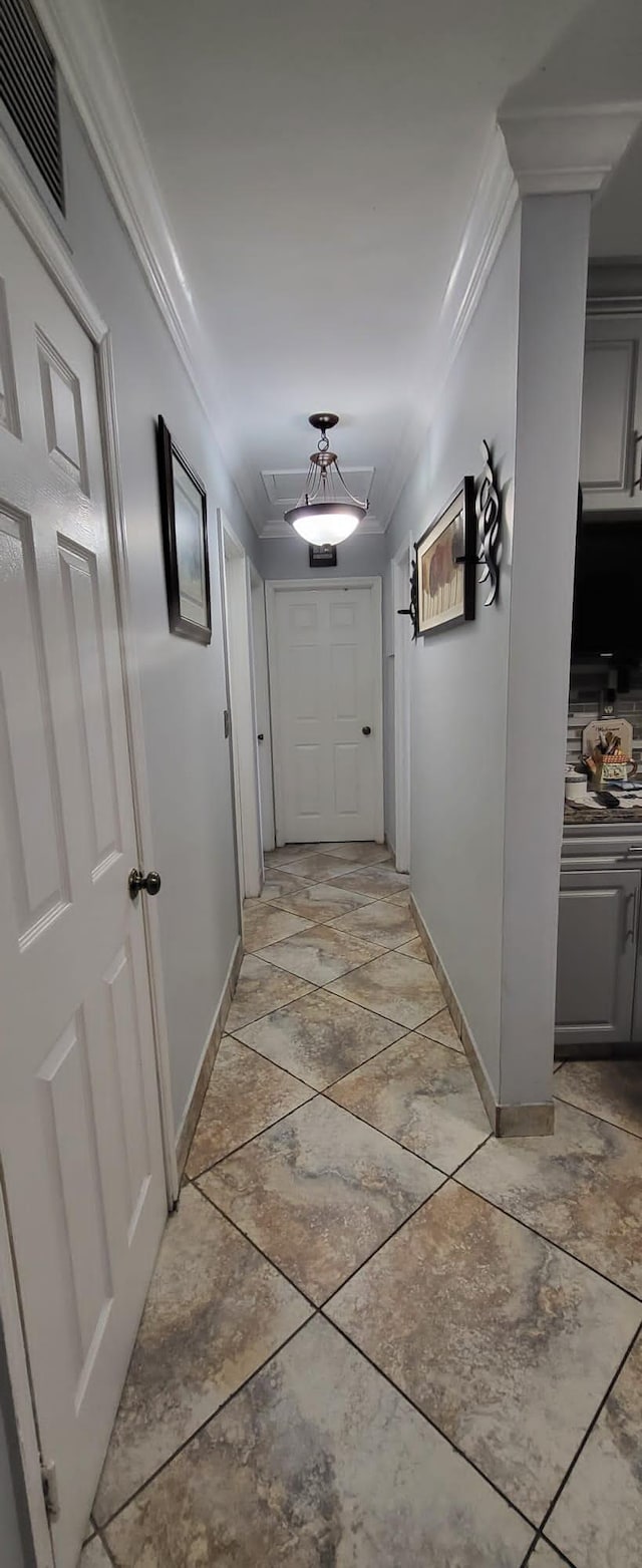 corridor with light tile patterned flooring and crown molding