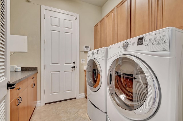 laundry area with cabinets, washing machine and dryer, and light tile patterned floors