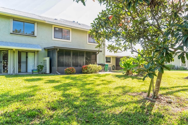 rear view of property featuring a sunroom and a yard