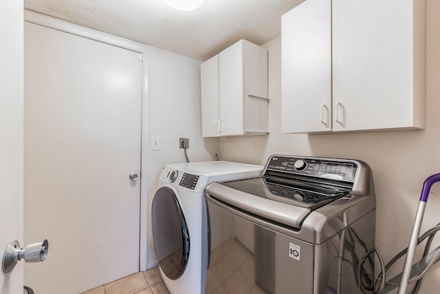 washroom featuring light tile patterned flooring, cabinets, and washing machine and dryer